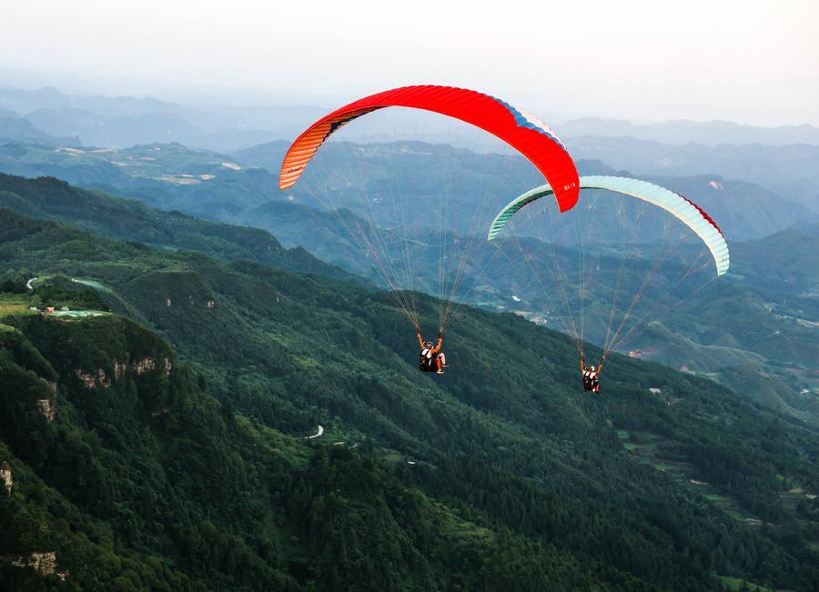 An aerial photo taken on July 30, 2026 shows tourists experiencing paragliding with pilots at a paragliding base in Jiuzhou Town, Huangping County, southwest China's Guizhou Province. (Xinhua/Yang Wenbin)