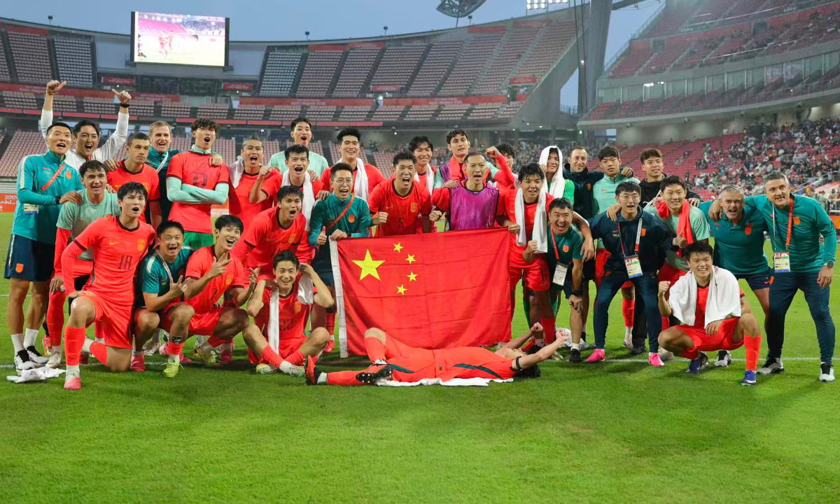 China's Asian Games men's football squad pose with the national flag on the field to celebrate their 3-0 victory over Thailand, which secured their spot in the Asian Games semi-finals after 28 years. Photo: Tao Xiang'an/People's Daily