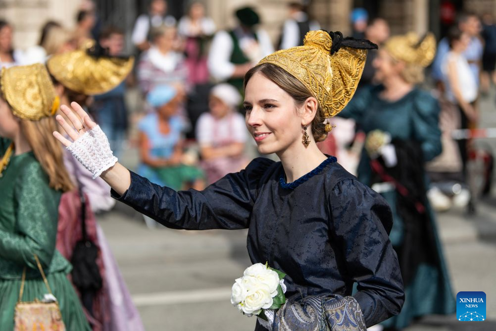 People greet the crowds during the Oktoberfest parade in Munich, Germany, Sept. 20, 2026. The 191st Oktoberfest, one of the largest folk festivals in Germany, opened on Saturday in Munich, and will last until Oct. 4. (Xinhua/Zhang Haofu)