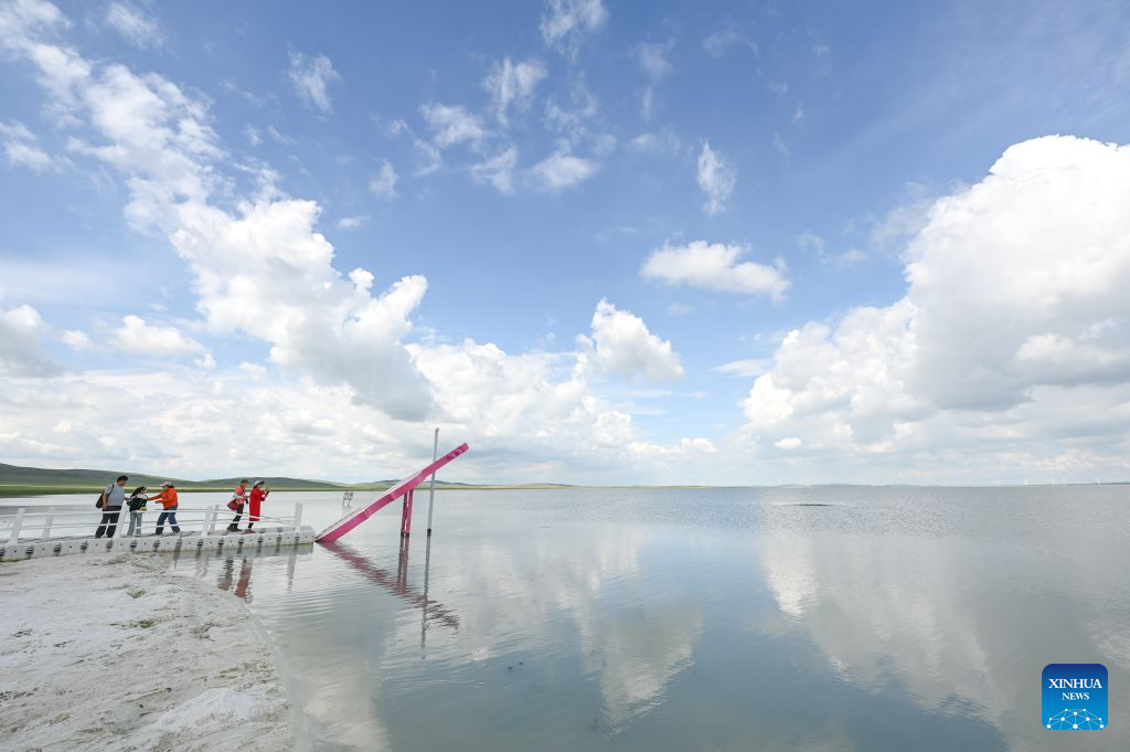 Tourists visit Baiyin Chagan Lake, or Milky Lake, in Xilin Gol League, north China's Inner Mongolia Autonomous Region, Aug. 4, 2026. The lake is dubbed Milky Lake as tiny mineral particles float in the water, turning it creamy-white like milk. (Xinhua/Lian Zhen)