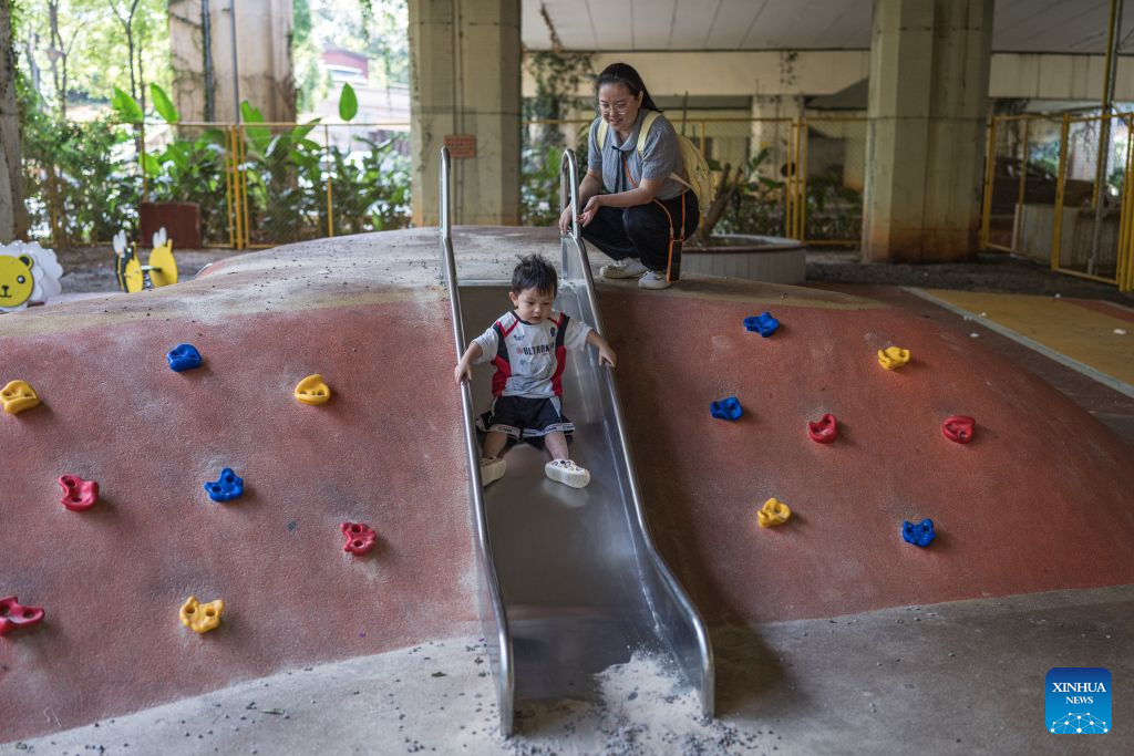 A child plays at a playground beneath a flyover in Kunming, southwest China's Yunnan Province, Aug. 11, 2026. In recent years, Kunming has transformed some vacant areas beneath urban bridges and flyovers into public spaces for greenery, leisure, recreation and physical exercises, making the city more livable for residents. (Xinhua/Wang Guansen)