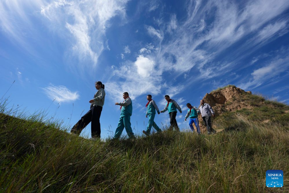 Yao Jian (1st R), Ma Lirong (1st L) and students take part in an extracurricular activity at the Sandun section of the Great Wall in Sandun Village, Huayuantun Town of Datong, north China's Shanxi Province, Sept. 9, 2026. (Xinhua/Yang Chenguang)