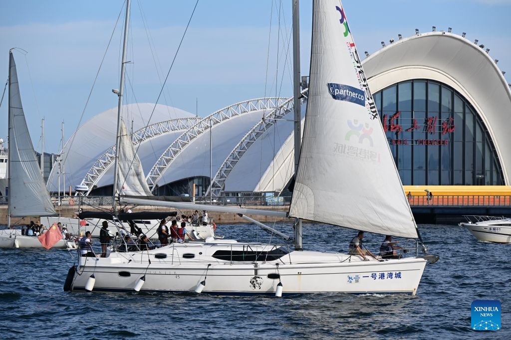 Tourists enjoy the views by boat along the coastline in Qingdao, east China's Shandong Province, Aug. 26, 2026. The Qingdao Olympic Sailing and Marine Culture Tourism Area has been promoting sea sightseeing by launching a number of sightseeing routes linking destinations from Jiaozhou Bay to Zhaitang Island, helping boost local tourism. (Xinhua/Li Ziheng)