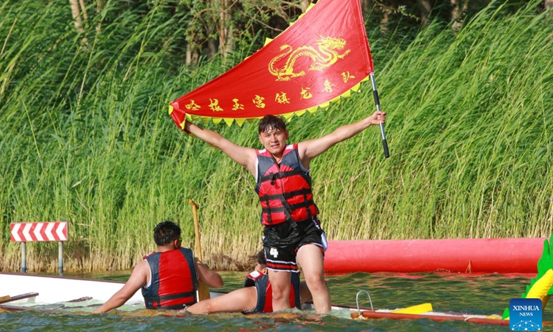 Anwar Kurban (R) celebrates after finishing the 2026 dragon boat race on Hongyan River in Korla City, northwest China's Xinjiang Uygur Autonomous Region, June 20, 2026. (Photo by Ai Houwei/Xinhua)