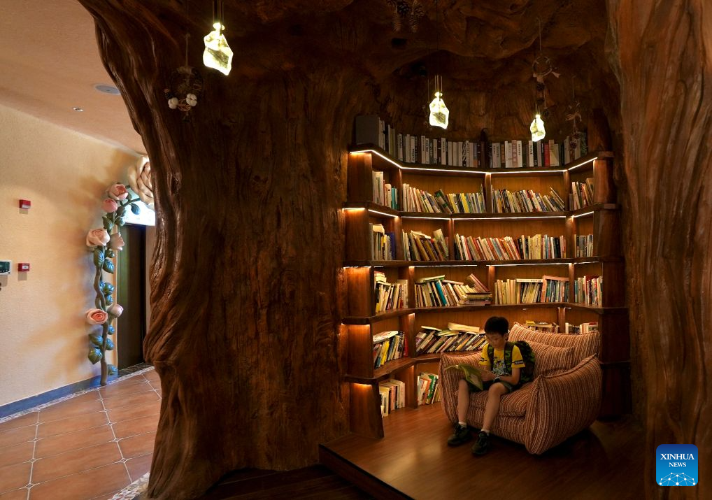 A child reads a book at a sinkhole-turned library in Wuyuan County, east China's Jiangxi Province on Aug. 26, 2026. A special sinkhole-turned library opened to the public recently in Wuyuan County of east China's Jiangxi Province. It incorporates a natural sinkhole and surrounding rock walls into its architecture. The library features a carved spiral staircase and warm lighting, offering visitors a distinctive reading experience. (Xinhua/Hu Chenhuan)