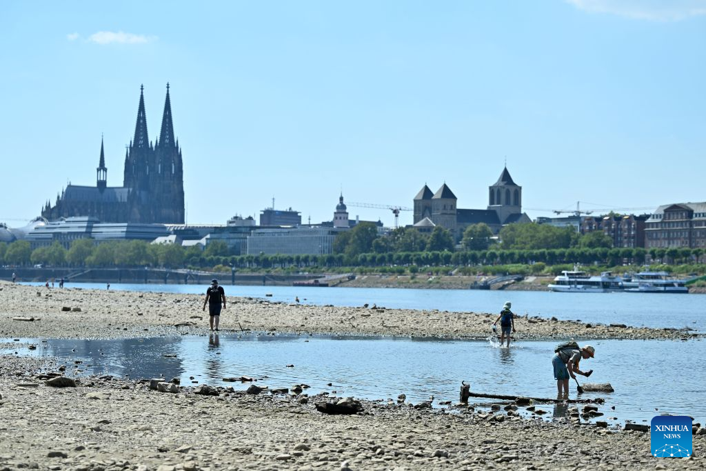 People enjoy themselves on the banks of the Rhine River in Cologne, Germany, Aug. 10, 2026. Persistent drought has caused water levels to fall along several sections of the Rhine River in Germany. (Photo by Ulrich Hufnagel/Xinhua)