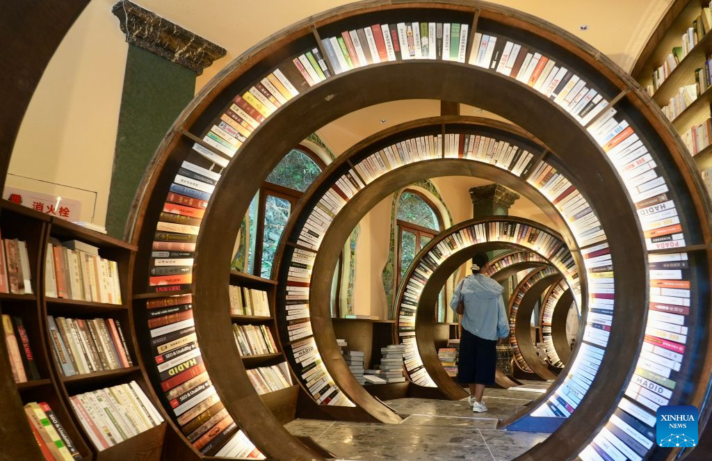 A woman visits a sinkhole-turned library in Wuyuan County, east China's Jiangxi Province on Aug. 26, 2026. A special sinkhole-turned library opened to the public recently in Wuyuan County of east China's Jiangxi Province. It incorporates a natural sinkhole and surrounding rock walls into its architecture. The library features a carved spiral staircase and warm lighting, offering visitors a distinctive reading experience. (Xinhua/Hu Chenhuan)