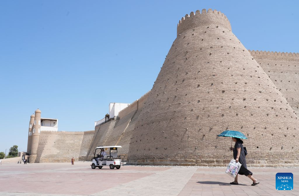 A pedestrian carries an umbrella to shield herself from the sun in front of the Ark of Bukhara in Bukhara, Uzbekistan, Aug. 3, 2026. The historic city of Bukhara in southwestern Uzbekistan is currently gripping with severe heat, with daytime highs consecutively exceeding 35 degrees Celsius. (Photo by Zafar Khalilov/Xinhua)