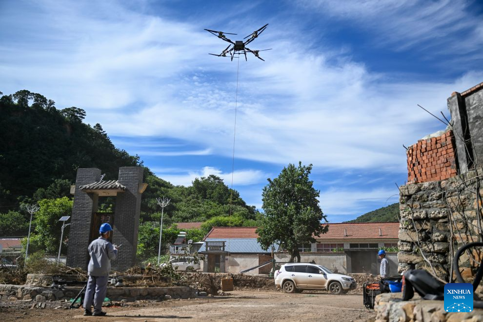 A staff member uses a drone to deliver an emergency power supply in Baimutang Village, Kuancheng Manchu Autonomous County of Chengde, north China's Hebei Province, July 14, 2026. Recently, heavy rainfall lashed four townships and nine villages in Kuancheng Manchu Autonomous County. Local authorities have launched relief efforts to restore infrastructure and normal life. (Photo by Wang Liqun/Xinhua)