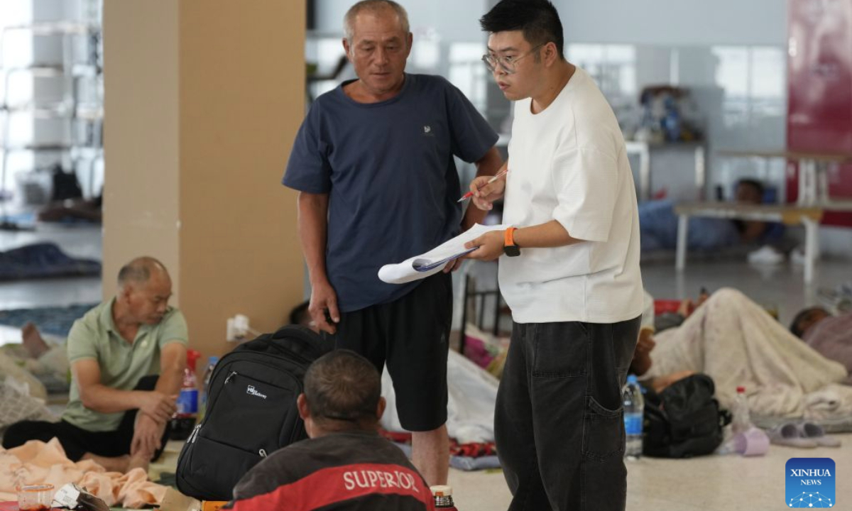 A staff member (R) inquires about people's need at a resettlement site at a middle school in Yuhuan City, east China's Zhejiang Province, Aug. 27, 2026. East China's Zhejiang Province raised its typhoon emergency response to Level I, the highest level, at 8 p.m. Thursday as Typhoon Saudel, the 18th typhoon of this year, is forecast to make landfall in the province. (Xinhua/Huang Zongzhi)