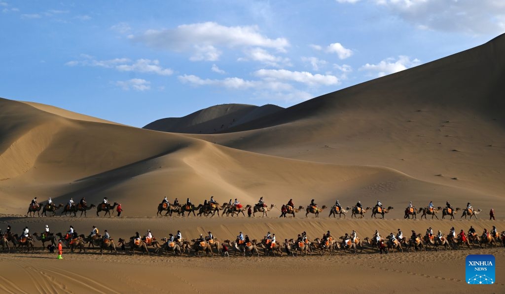 Tourists ride camels at the Mingsha Mountain and Crescent Spring Scenic Area in Dunhuang, northwest China's Gansu Province, June 19, 2026. People enjoyed the three-day holiday of the Dragon Boat Festival, also called Duanwu Festival, which falls on June 19 this year, via various activities across the country. (Photo: Xinhua)