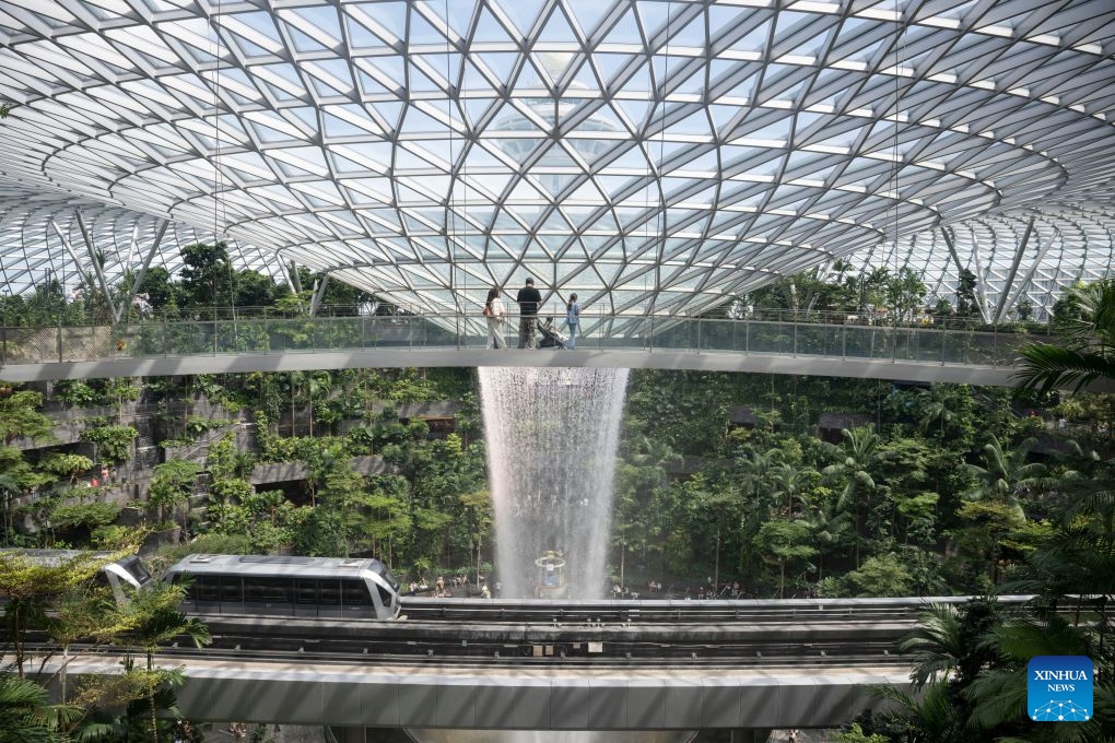 People take photos of the indoor man-made waterfall Rain Vortex at Jewel Changi Airport in Singapore, June 23, 2026. (Photo: Xinhua)