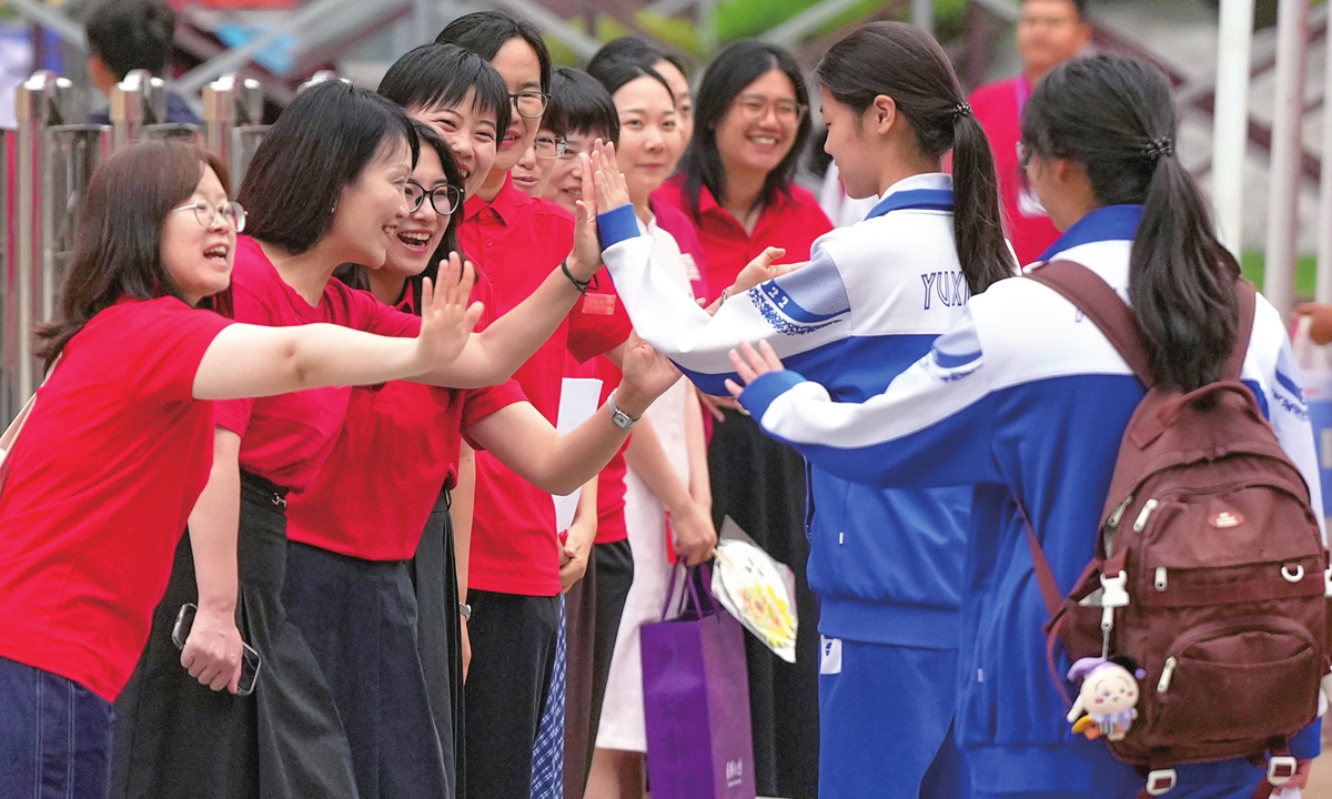 Candidates entering a high school entrance exam venue in Beijing high-five their teachers before going in on June 24, 2026. The 2026 Beijing high school entrance exam is held from June 24 to June 25 and includes four subjects. Photo: VCG