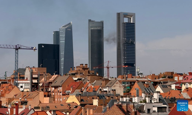 This photo taken on June 23, 2026 shows smoke rising from Torre Moeve tower in Madrid, Spain. A fire broke out at Madrid's Torre Moeve, the city's second-tallest tower, on Tuesday, with smoke seen rising from the skyscraper from multiple locations across the city. According to local media, Madrid's emergency services confirmed that people inside the building are being evacuated and that traffic in the surrounding area has been disrupted. The cause of the fire remains unknown. (Photo: Xinhua)