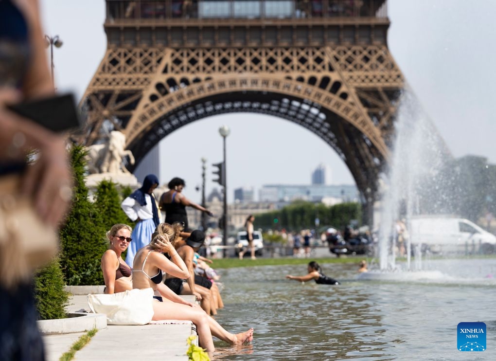 People cool off and relax at a fountain in front of the Eiffel Tower in Paris, France, June 23, 2026. The Eiffel Tower in Paris closed early on Tuesday due to high temperature. (Photo: Xinhua)
