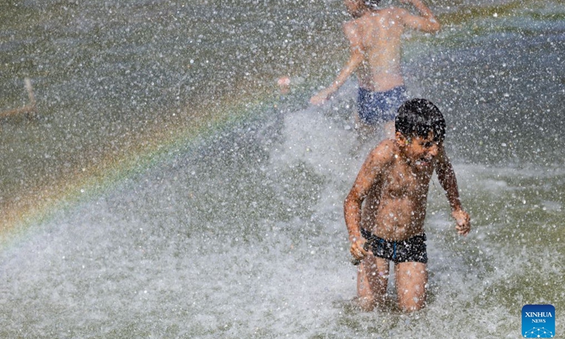 Children cool off and relax at a fountain in front of the Eiffel Tower in Paris, France, June 23, 2026. The Eiffel Tower in Paris closed early on Tuesday due to high temperature. (Photo: Xinhua)