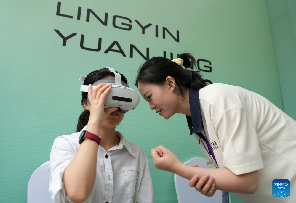 A visitor tries out a VR headset on an AI exhibition by the West Lake in Hangzhou, east China's Zhejiang Province, June 24, 2026. New applications of artificial intelligence and embodied intelligence in the cultural and tourism sector from 15 leading technology companies were displayed at the exhibition. (Photo: Xinhua)