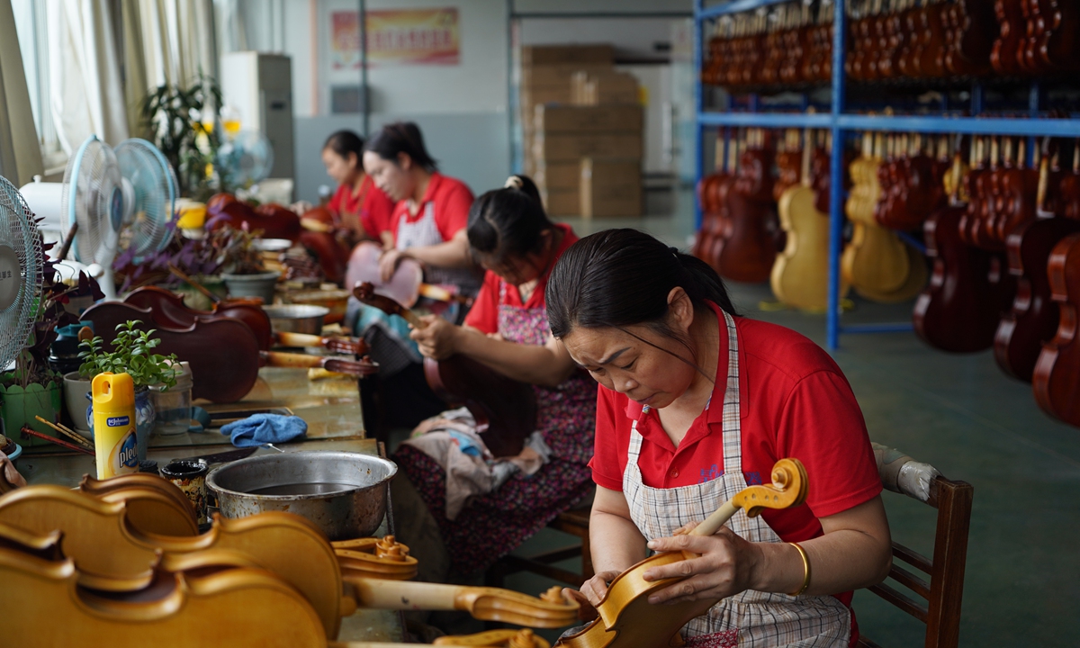 Employees handcraft violins at a workshop in Queshan county, Central China's Henan Province on June 25, 2026. Dubbed the 