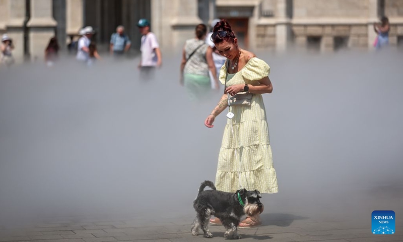A woman and her dog cool off with a mist cooling system amid a heatwave in Budapest, Hungary, June 24, 2026. Hungarian authorities on Tuesday extended a nationwide second-degree heat alert until midnight on June 26 and announced that the warning level would be raised to a third-degree, the highest level, from June 27 through June 30 as extreme temperatures persist across the country. (Photo: Xinhua)