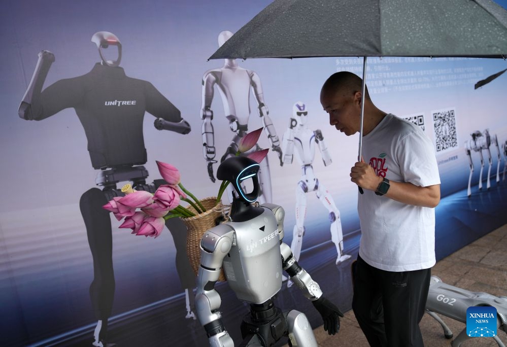 A visitor looks at a robot developed by Unitree Robotics during an AI exhibition by the West Lake in Hangzhou, east China's Zhejiang Province, June 24, 2026. New applications of artificial intelligence and embodied intelligence in the cultural and tourism sector from 15 leading technology companies were displayed at the exhibition. (Photo: Xinhua)