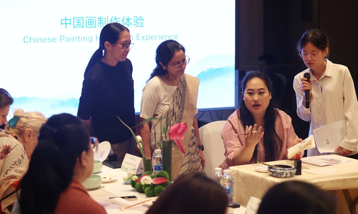 A professional ink painting instructor explains traditional Chinese painting techniques to Chinese and foreign guests on site.
