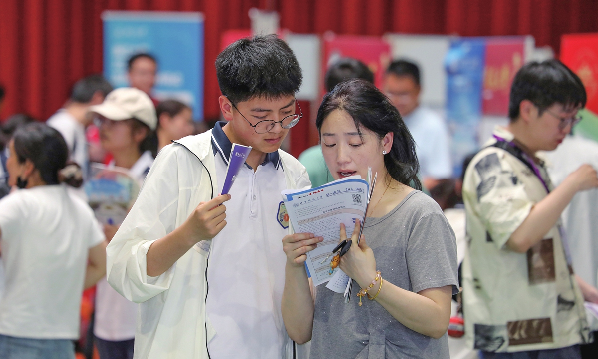A student and his parent browse university recruitment materials at an admissions consultation fair held at a middle school in Baoying, East China's Jiangsu Province. As China's college entrance examination scores are being released across China, universities nationwide start launching annual admissions campaigns. Photo: VCG