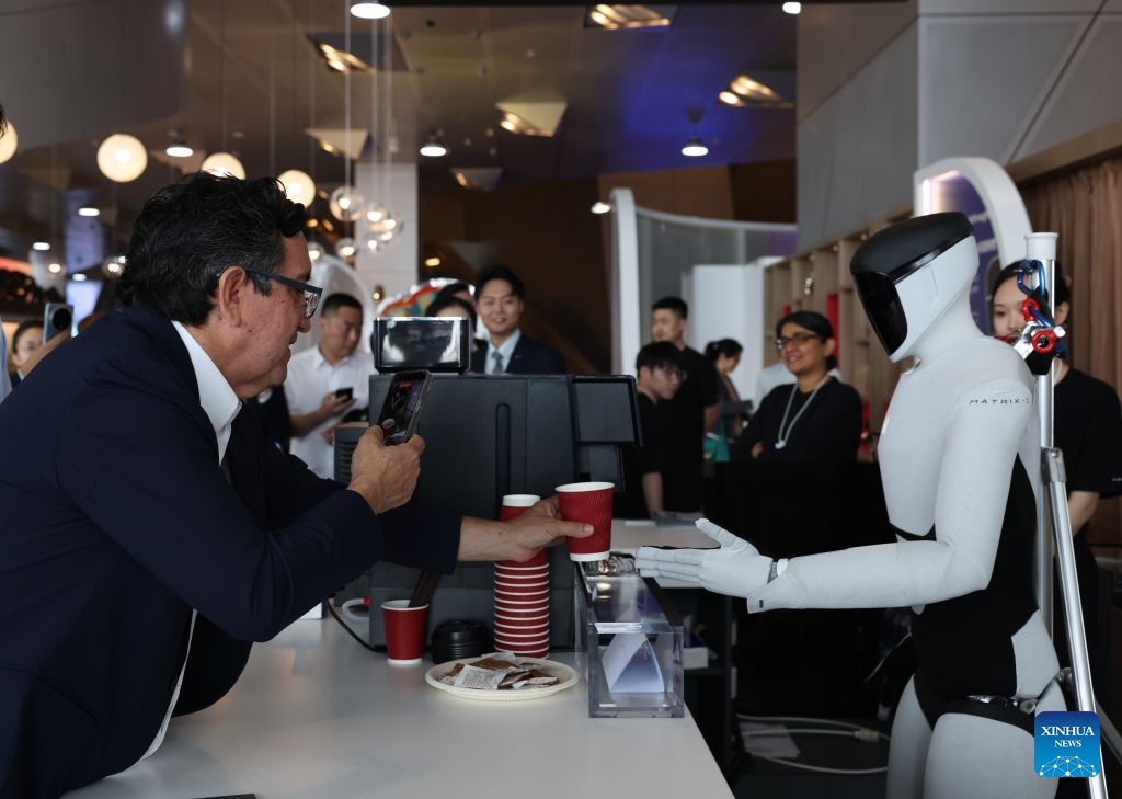 A robot makes a cup of coffee for a participant during the 17th Annual Meeting of the New Champions, also known as the Summer Davos, at the Dalian International Conference Center in Dalian, northeast China's Liaoning Province, June 24, 2026. Featuring the theme Innovating at Scale, the event is held from June 23 to 25. Over 30 subjects related to artificial intelligence and robotics are among the hot topics at this year's forum. (Photo: Xinhua)
