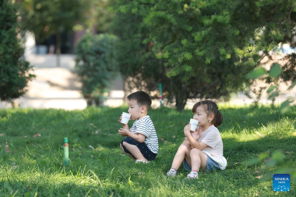 Children drink beverages under the trees in Bishkek, Kyrgyzstan, June 25, 2026. (Photo by Roman/Xinhua)