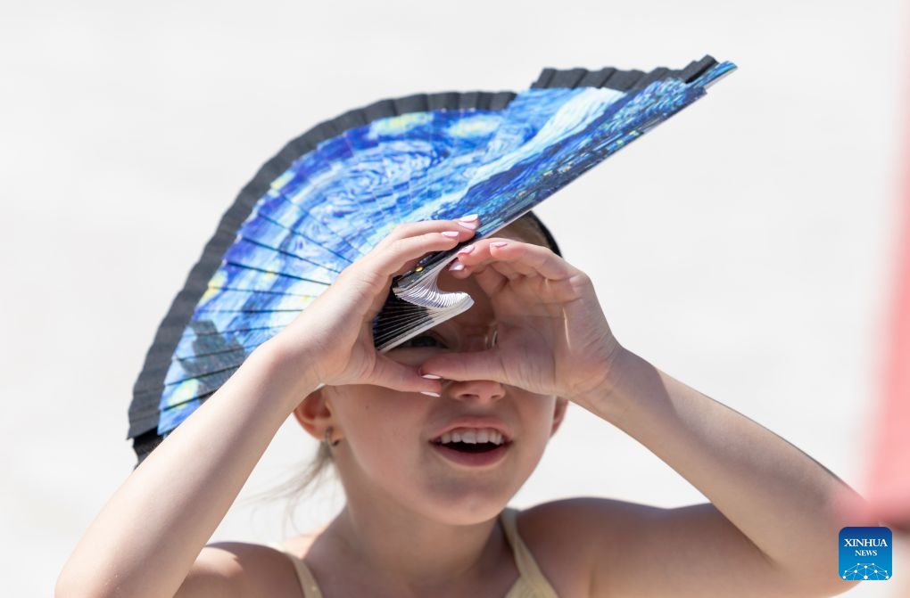 A girl uses a folding fan to shield herself from the sun amid the heatwave, in Paris, France, June 25, 2026. (Xinhua/Wu Huiwo)