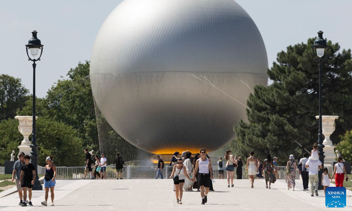 Visitors walk in front of the Paris 2024 Olympic cauldron near the Louvre Museum amid the heatwave, in Paris, France, June 25, 2026. (Xinhua/Wu Huiwo)
