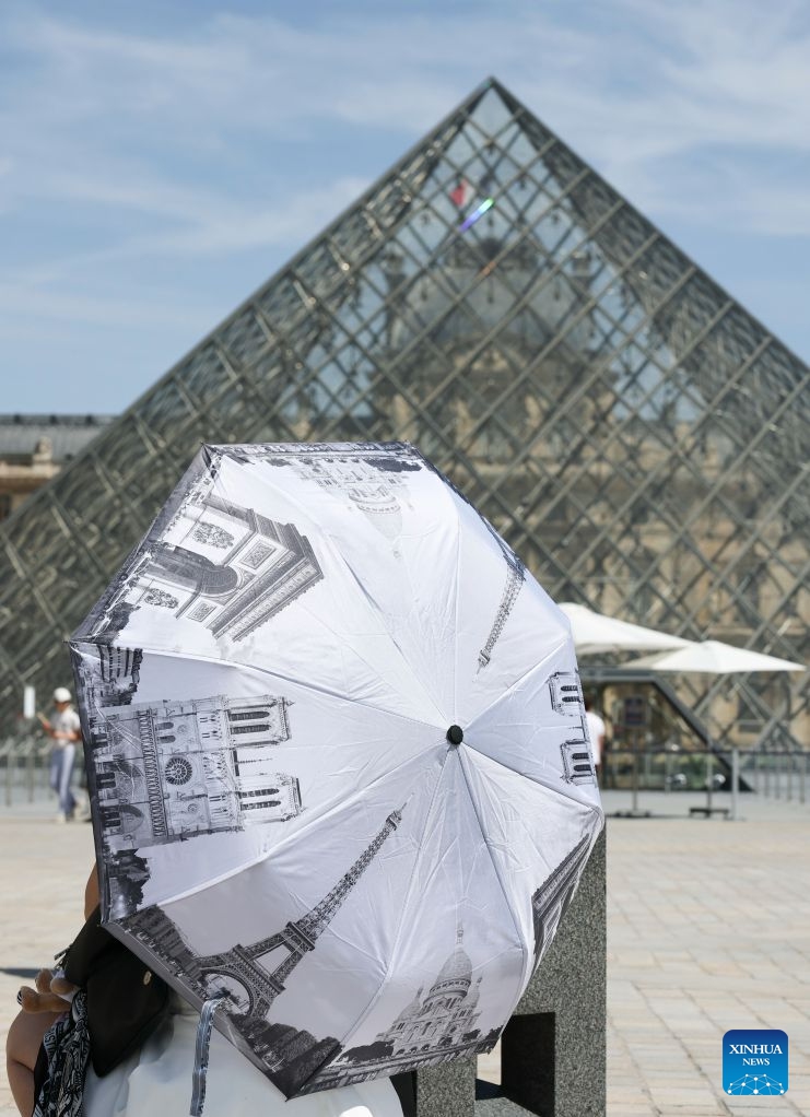 A woman holding an umbrella is seen near the Louvre Museum amid the heatwave, in Paris, France, June 25, 2026. (Xinhua/Wu Huiwo)