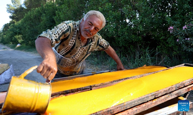 A Syrian worker pours apricot puree onto wooden boards to dry to make Qamar al-Din, a traditional fruit sweet, at a workshop in the countryside of Damascus, Syria, on June 25, 2026. Made during the apricot harvest season, Qamar al-Din is produced by washing and pressing fresh apricots before spreading the fruit puree onto wooden boards to dry naturally under the sun, a traditional process that has been practiced in Syria for generations. (Photo: Xinhua)