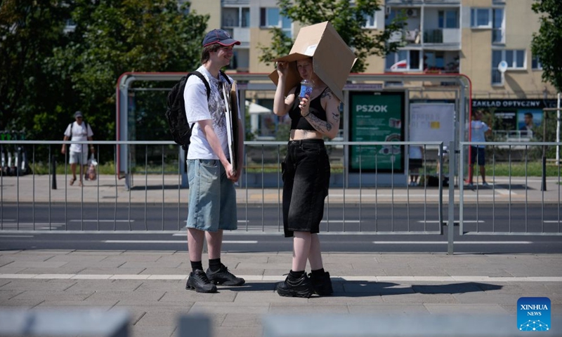 A woman shields herself from the scorching sun with a cardboard box in Warsaw, Poland, June 27, 2026. Poland's Institute of Meteorology and Water Management has issued its highest, third-level heat warnings from Saturday morning to Monday evening. The peak of the extreme heat event is expected on Sunday, when temperatures in some regions could reach up to 42 degrees Celsius, the weather service said. (Photo by Jaap Arriens/Xinhua)

