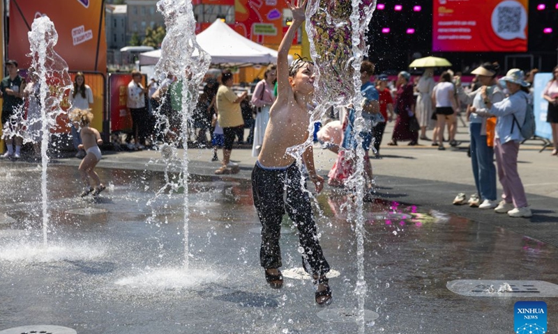 A boy plays in the fountain in Vladivostok, Russia, June 27, 2026. As temperature in Vladivostok rises significantly, people have flocked to the streets and the seaside to enjoy their summer time. (Photo by Andrey Matveenko/Xinhua)

