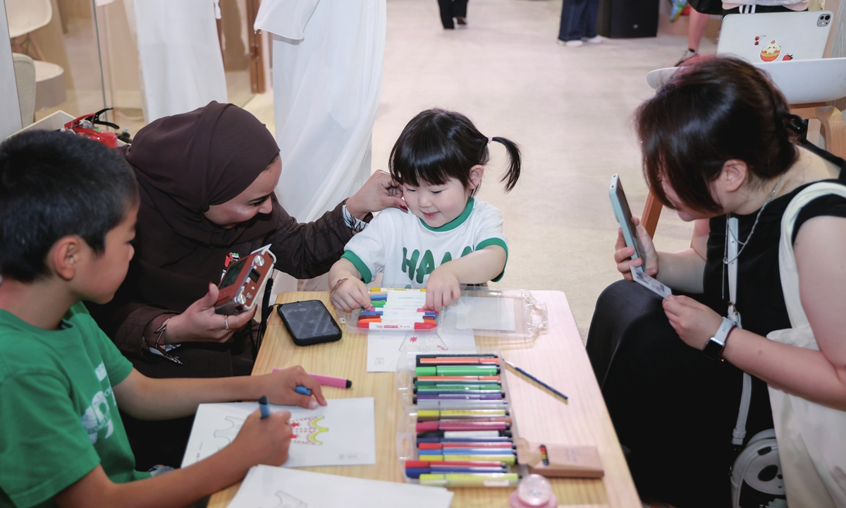 Chinese visitors interact with an exhibitor at the Children's Corner of the 