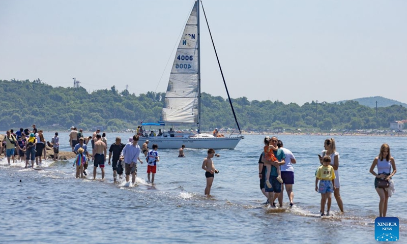 People enjoy themselves on the seaside in Vladivostok, Russia, June 27, 2026. As temperature in Vladivostok rises significantly, people have flocked to the streets and the seaside to enjoy their summer time. (Photo by Andrey Matveenko/Xinhua)

