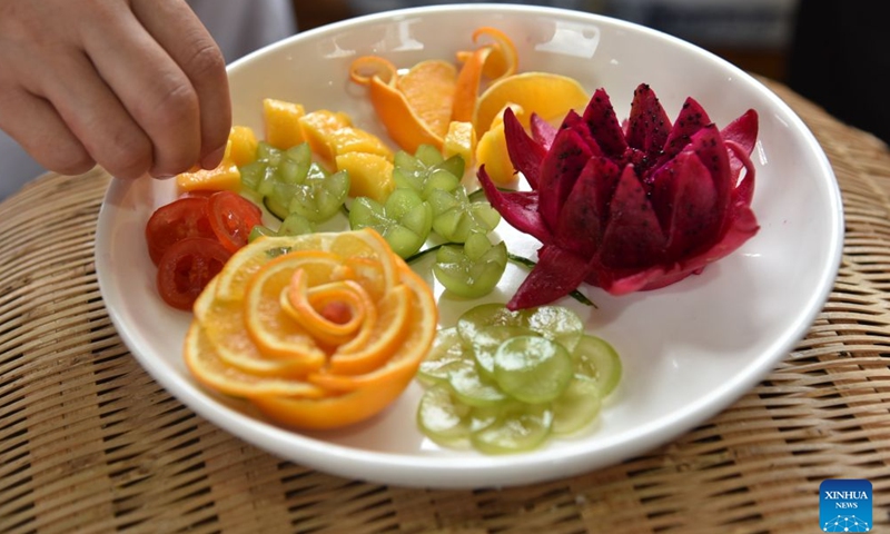 A contestant competes in fruit carving at an event themed on village flavors in Shiqian County, Tongren City, southwest China's Guizhou Province, June 28, 2026. A series of events themed on village flavors were held in Shiqian County over the weekend. More than 10 village- or community-based teams competed in cuisine contests using local ingredients such as Shiqian moss tea and seasonal produce. Parades featuring intangible cultural heritage, recreational competitions and other activities were also held to showcase local cuisine and rural traditions. (Xinhua/Li Fan)

