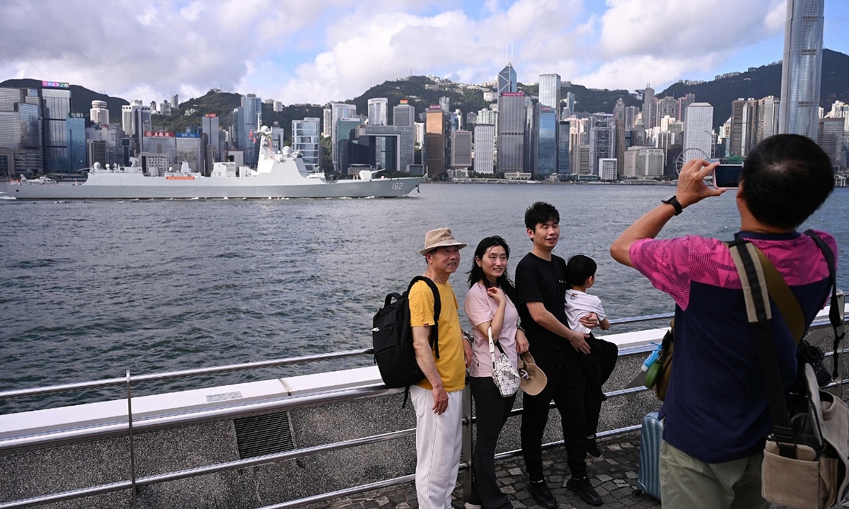 Tourists take photos as the Chinese People's Liberation Army (PLA) Navy guided-missile destroyer Nanning sails across Victoria Harbour, arriving in Hong Kong for a five-day visit on July 2, 2026. Photo: VCG