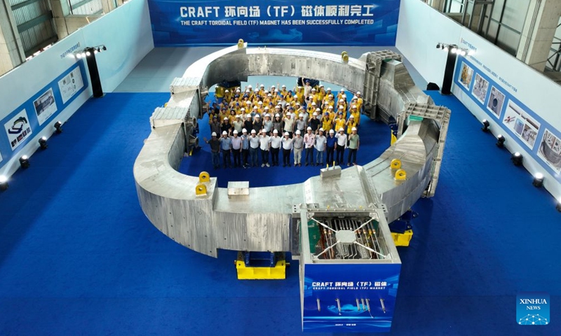 A drone photo taken on June 27, 2026 shows technicians and experts posing for group photos with the toroidal-field superconducting magnet for the fusion reactor in Hefei, east China's Anhui Province.
