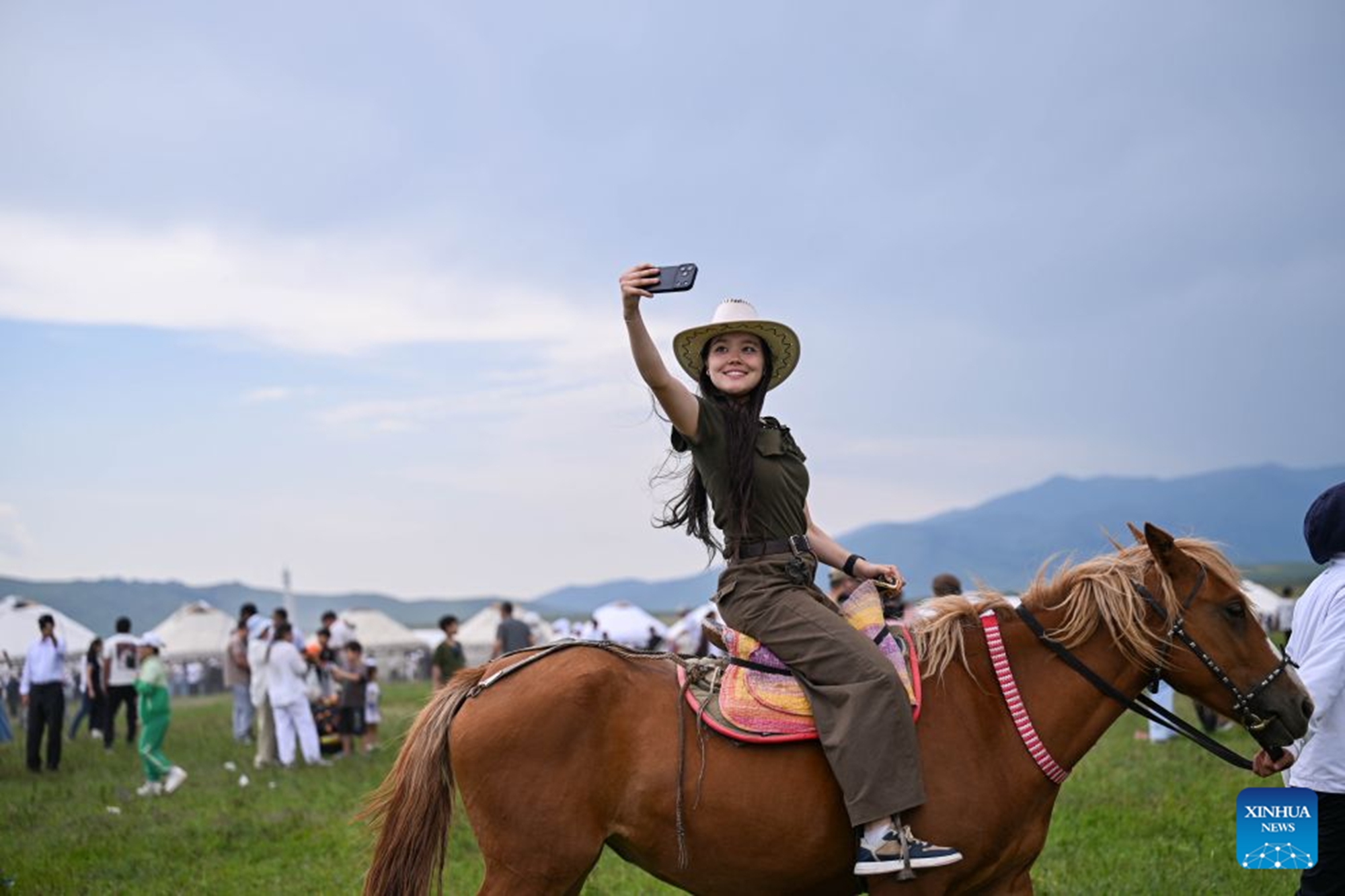 A woman takes a selfie while riding a horse during a grand ethnic cultural event in Karkara, Almaty Region, Kazakhstan, on June 27, 2026. (Xinhua/Li Renzi)


