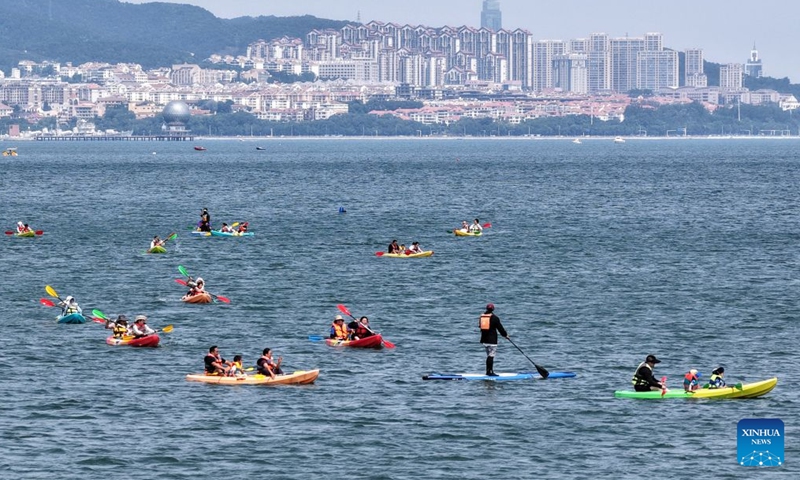 A drone photo shows people enjoy water activities at a bathing beach in Yantai City, east China's Shandong Province, June 28, 2026. (Photo by Tang Ke/Xinhua)


