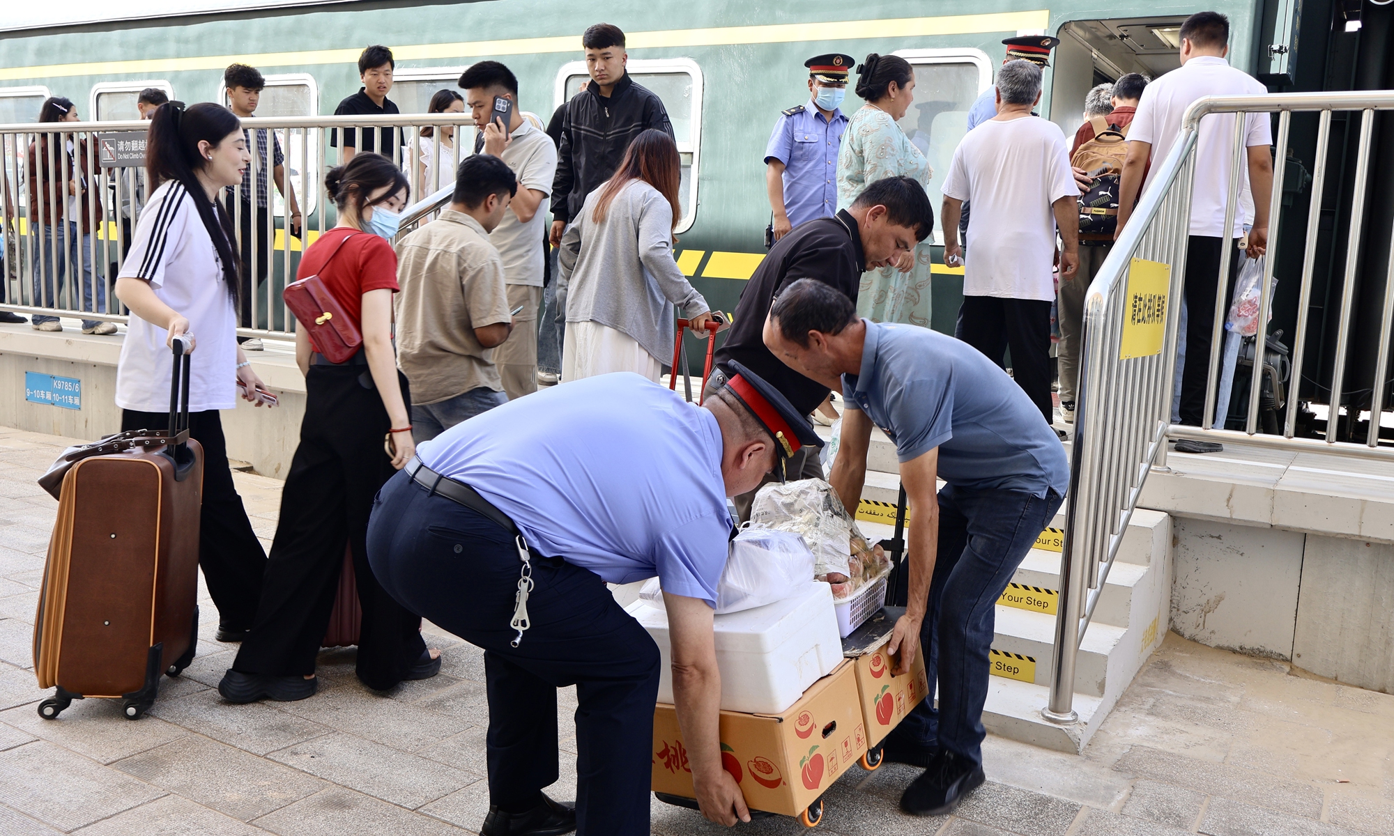 Polatkhan, chief conductor of Train No. 7558, helps vendors from Hotan Prefecture carry products onto the train on June 25, 2026. Photo: Lin Xiaoyi/GT