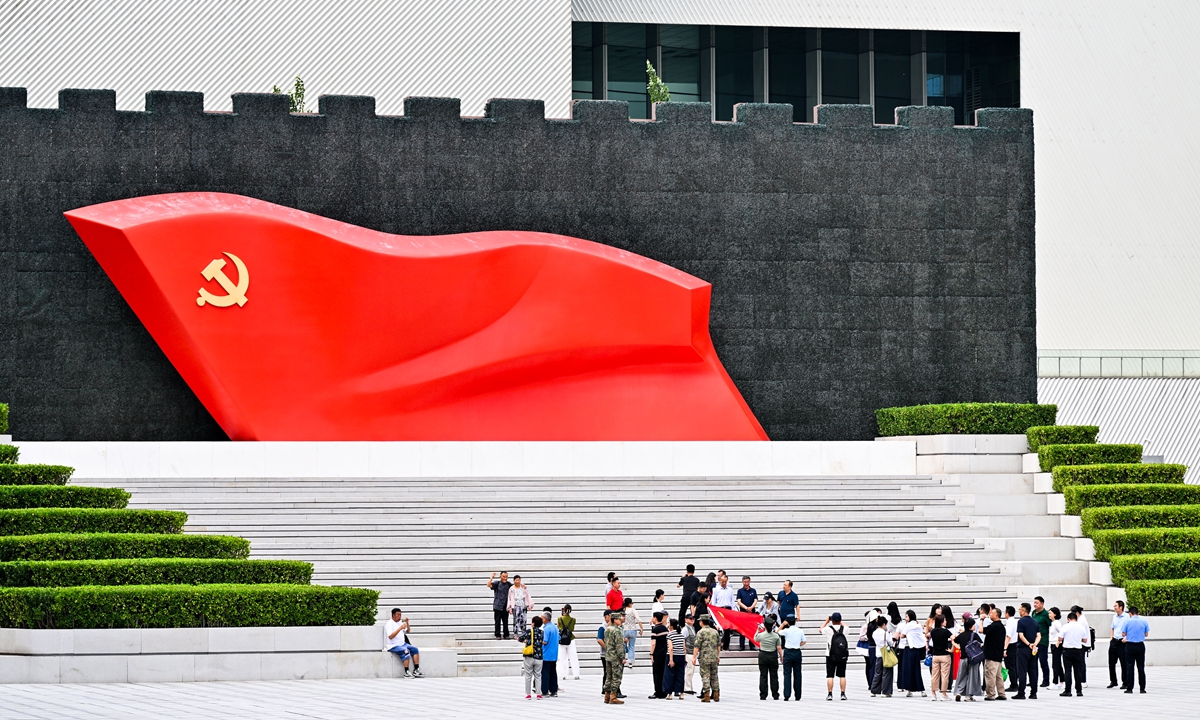 Members of various grass-roots Party organizations gather in front of the giant Party flag outside the Museum of the Communist Party of China (CPC) in Beijing on June 30, 2026, to take commemorative photos and participate in the 