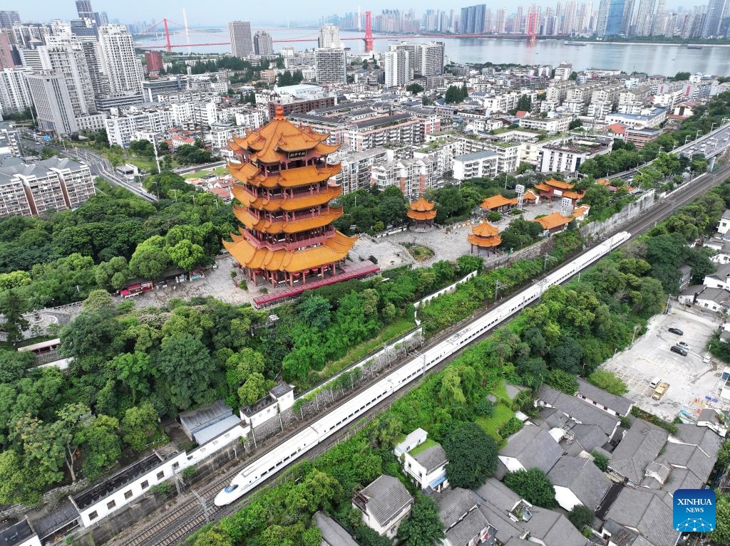 A drone photo taken on June 30, 2026 shows a high-speed train running past the Yellow Crane Tower scenic area in Wuhan, central China's Hubei Province. Starting from 00:00 on July 1, China's railway diagram will be adjusted by adding 106 passenger train services and 111 freight train service to the current schedule. After the adjustment, a total of 12,174 passenger trains will be scheduled nationwide, while 23,975 freight trains will be operated. (Photo by Zhao Jun/Xinhua)