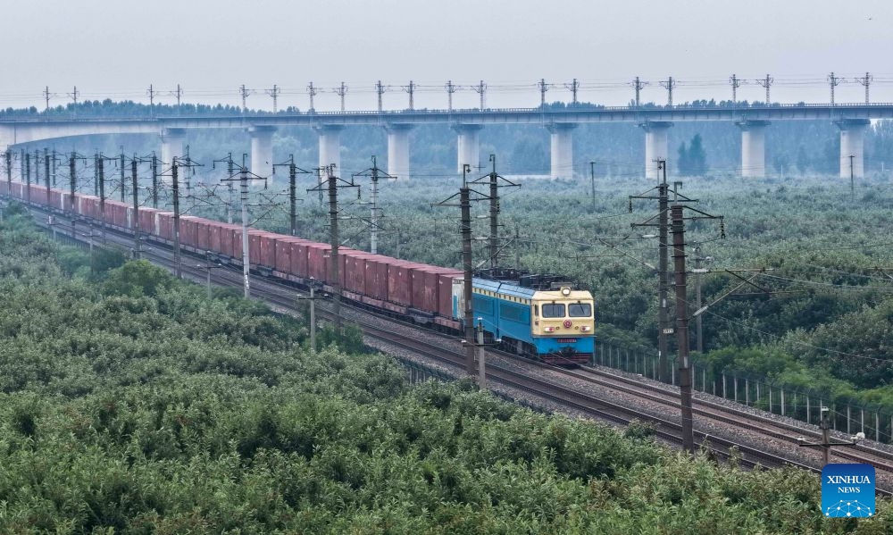 A drone photo taken on June 30, 2026 shows a coal freight train running in Zunhua City, north China's Hebei Province. Starting from 00:00 on July 1, China's railway diagram will be adjusted by adding 106 passenger train services and 111 freight train service to the current schedule. After the adjustment, a total of 12,174 passenger trains will be scheduled nationwide, while 23,975 freight trains will be operated. (Photo by Liu Mancang/Xinhua)