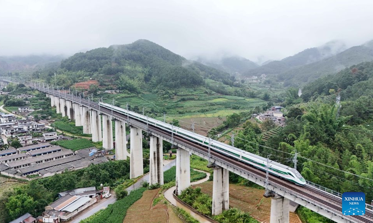 A drone photo taken on June 30, 2026 shows a high-speed train running in Ning'er Hani and Yi Autonomous County, Pu'er City, southwest China's Yunnan Province. Starting from 00:00 on July 1, China's railway diagram will be adjusted by adding 106 passenger train services and 111 freight train service to the current schedule. After the adjustment, a total of 12,174 passenger trains will be scheduled nationwide, while 23,975 freight trains will be operated. (Photo by Yang Tingrong/Xinhua)