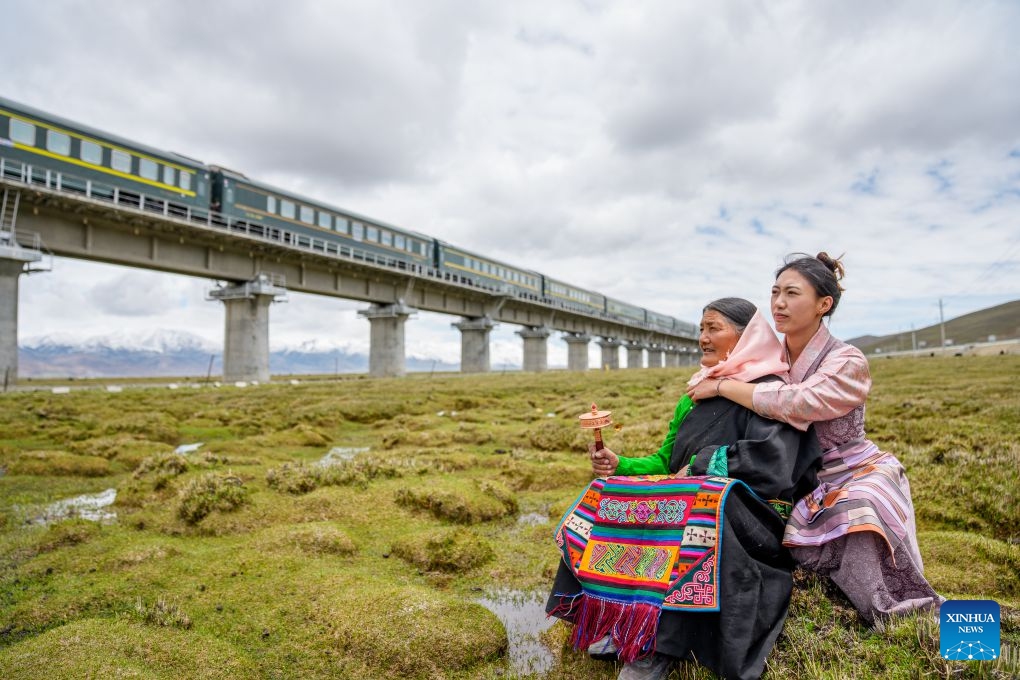 Nyima Lhamo (R) and her mother Pema Lhamo gaze at a passing train in Damxung County of Lhasa, southwest China's Xizang Autonomous Region, May 28, 2026. (Xinhua/Tenzin Nyida)
