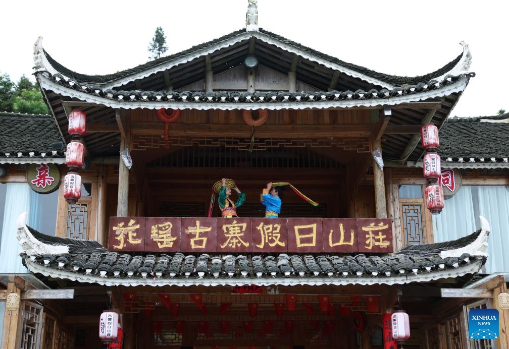 Tourists try costumes of Tiaohua cross-stitch embroidery in Longhui County of Shaoyang, central China's Hunan Province, June 23, 2026. Tiaohua cross-stitch embroidery is a traditional handicraft passed down through generations by women of Huayao, a branch of Yao ethnic group, in Longhui County.(Xinhua/Zhao Zhongzhi)