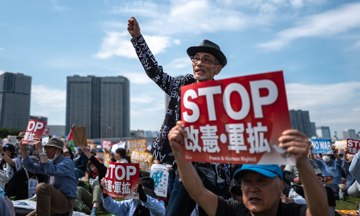 People attend a large-scale constitutional rally in Tokyo, holding placards reading 