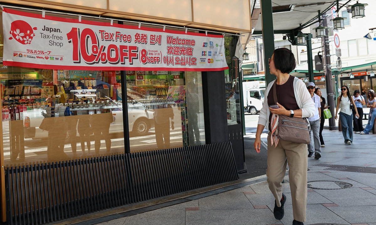 A foreign tourist walks past the tax-free sign banner displayed outside the shop  in Kyoto, Japan, on May 25, 2026. Photo: VCG